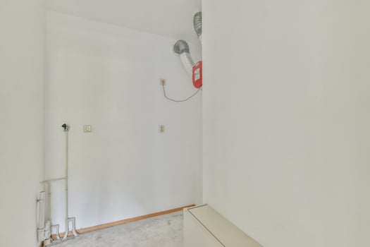 A white wall with a red fire hydrant in the corner photo
