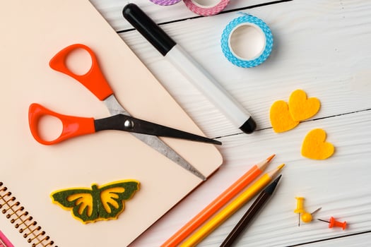 Colorful stationery arrangement with a butterfly sticker on a blank notebook at a wooden table in natural light photo