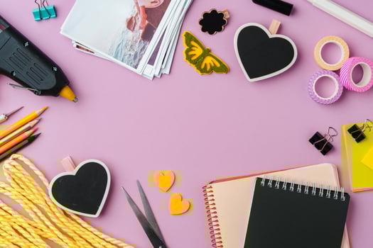 Crafting supplies arranged on a pink background, including glue gun, scissors, and decorative items for DIY projects photo