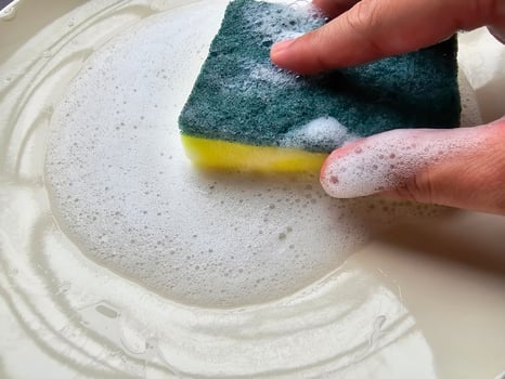 Closeup of washing dishes while rubbing a sponge on a plate. photo