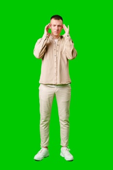 Man With Short Hair Wearing Beige Jacket Holding His Head in Frustration Against a Bright Green Background photo