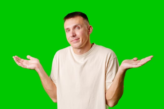 Young Man With Neutral Expression Shrugging His Shoulders Against Bright Green Background photo