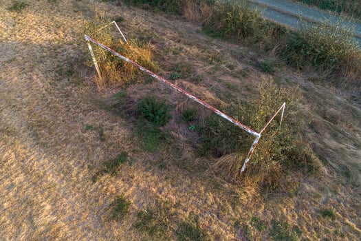 a goal of an abandoned football pitch covered by weeds, aerial top view from a drone photo