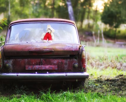 Vintage toned photo of the old bear toy on the retro rusty car outdoors