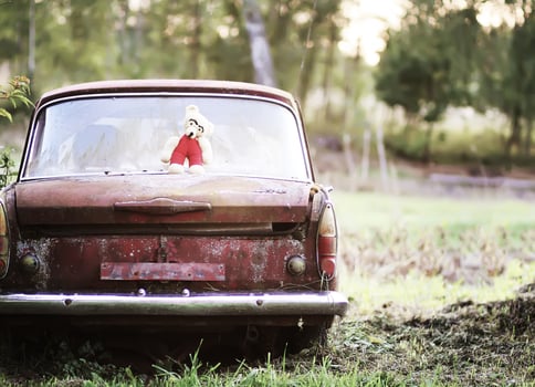 Vintage toned photo of the old bear toy on the retro rusty car outdoors