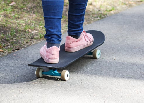 Child's legs on skateboard on asphalt road in park. photo