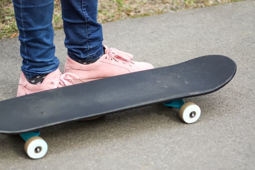 Child's legs on skateboard on asphalt road in park. photo