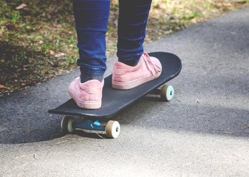 Child's legs on skateboard on asphalt road in park. photo