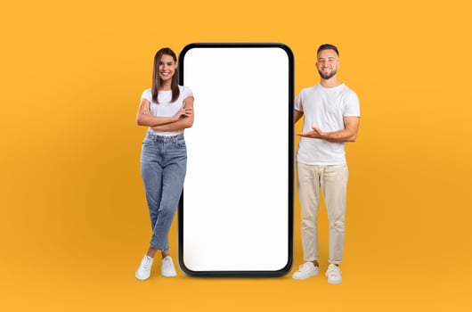 The young man and woman confidently stand by a smartphone with a blank screen, signaling a tech-savvy generation. photo