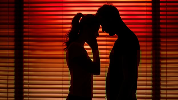 Couple stands in deep red light filtering through window blinds image. Woman man foreheads touching in moment of quiet intimacy photography. Togetherness concept photorealistic photo
