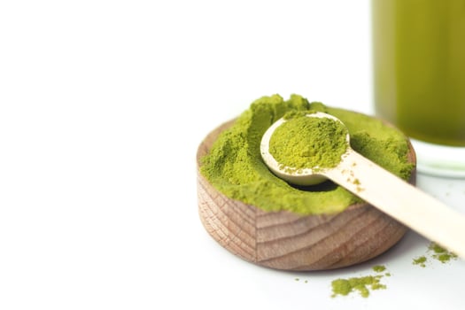 Wheatgrass organic powder in wooden bowl and spoon on white background with daily energy drink copy space photo