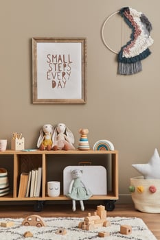 Stylish scandinavian newborn baby room with brown wooden mock up poster frame, plush animal and child accessories. Cozy decoration and hanging cotton flags on the beige wall. Template. photo