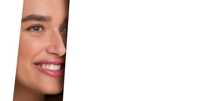 The image shows a woman face peeking through a perfectly circular hole in a white piece of paper. Her features are visible, framed by the edges of the hole. photo