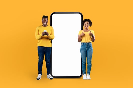 Positioned on a striking blue backdrop, the young black man and woman, both beaming, flank a giant smartphone awaiting your personalized content on its screen. photo