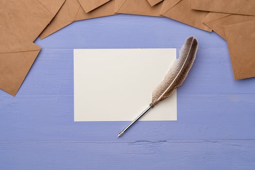 Blank paper with feather and envelopes on lavender wooden table photo