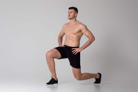 A man is exercising by performing squats on a gray background. He is bending his knees and lowering his hips, then pushing back up to a standing position photo