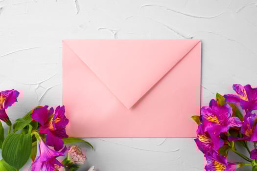 Pink envelope with flowers, top view. Romantic letter photo