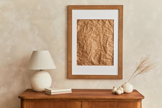 Minimalist composition of living room with brown mock up picture frame, table lamp, dried flower in vase, book, decoration and elegant personal accessories in stylish decor. Template. photo