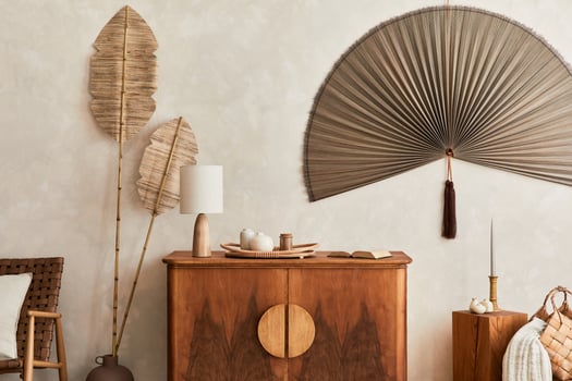 Japandi concept of living room interior with design wooden commode, table lamp, tropical dried leaf in vase, cubes, decoration, japanese fan and elegant accessories in home decor. Template. photo