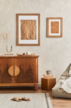 Interior design of neutral living room with stylish retro commode, mock up poster frame, table lamp, decoration and elegant personal accessories in home decor. Template. Japandi concept. photo