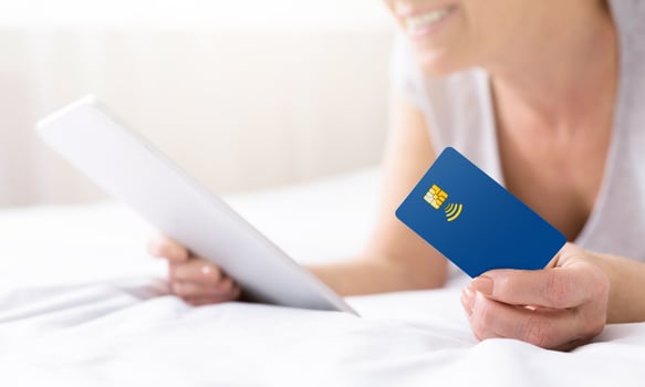 Senior woman doing online shopping through tablet PC and credit card in bed, panorama, free space photo