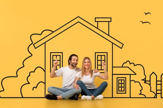 A man and a woman are seated on the floor, facing a large drawing of a house on a piece of paper. They appear to be studying the detailed features of the architectural design. photo