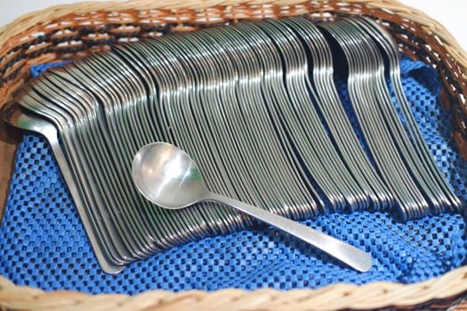 Stainless steel spoon in a wicker basket on a blue background photo