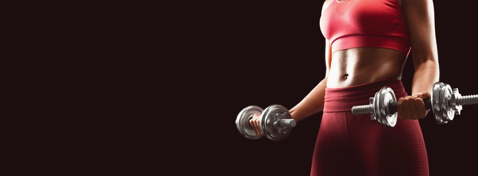 African fit girl holding barbells over black studio background, cropped, empty space photo