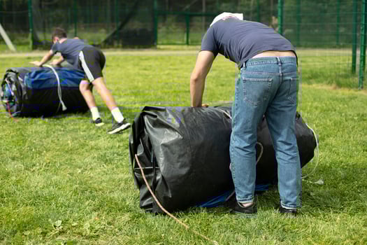 Men remove mats. Movers roll rolls. Stadium cleaning. Sports equipment. photo