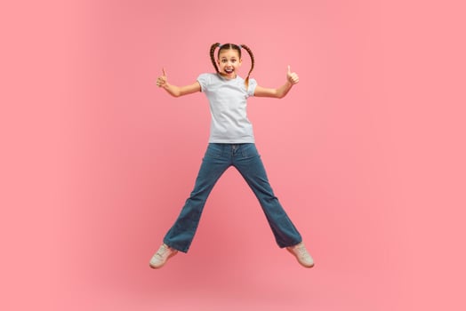 A young girl child is joyfully leaping into the air with her arms outstretched. She appears to be full of energy and excitement as she jumps high off the ground. photo