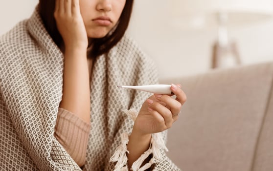 Must Be Sick. Sad Girl with Fever Measuring her Body Temperature, Sitting on Couch at Home photo