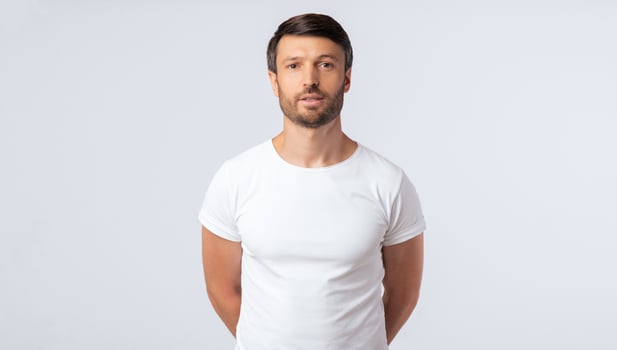 Serious Man Standing With Hands Behind His Back Looking At Camera On White Studio Background. Isolated, Free Space photo