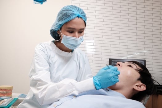 Asian female dentist examine young male patient teeth and toothache stomatology in dental clinic, well-being hygiene checks, and professional orthodontic healthcare work in doctor's office hospital. photo