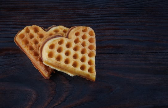 Two heart-shaped Viennese waffles lie on a dark wooden board. photo