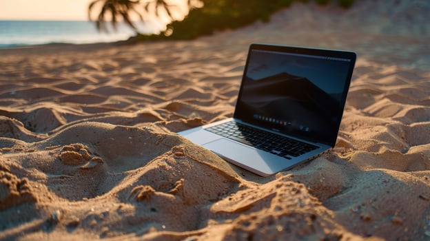 A laptop is sitting on the sand in front of the ocean photo