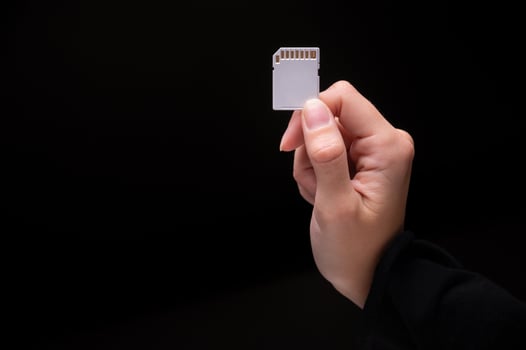 Female hand of caucasian woman holding sd flash card on black background photo