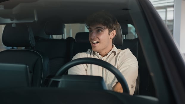 Happy Caucasian man driving new luxury electric crossover car in automobile salon dealership rejoice buy celebrate sitting inside cab auto transport credit loan emotions of happiness buyer achieve photo