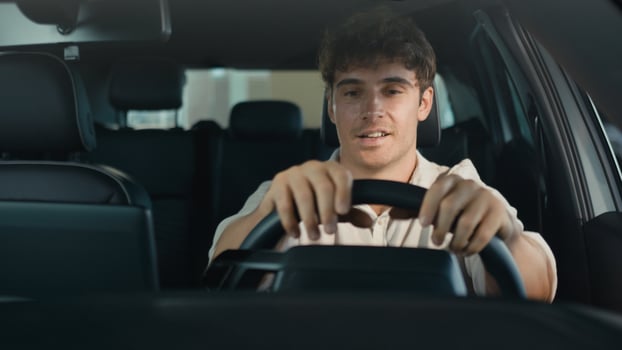 Happy Caucasian man driving new luxury electric crossover car in automobile salon dealership rejoice buy celebrate sitting inside cab auto transport credit loan emotions of happiness buyer achieve photo