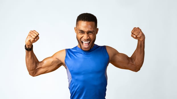 Yes You Can. Emotional black sportsman screaming, raising clenched fists in the air, yellow studio wall, panorama photo