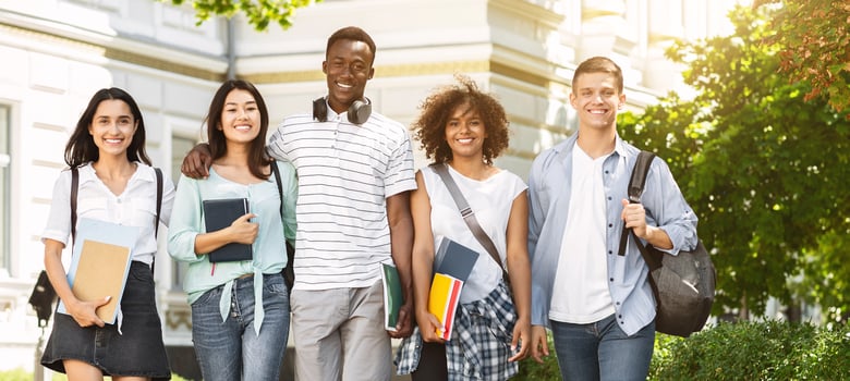 Portrait of happy international college students walking together in campus after classes, free space photo