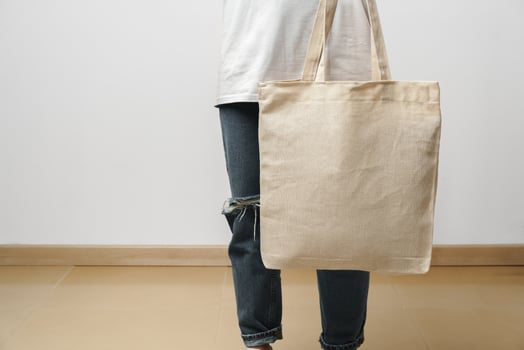 Cropped image of woman holding beige shopping bag in studio photo