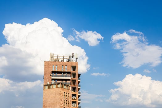 white clouds in blue sky and high-rise brick house photo