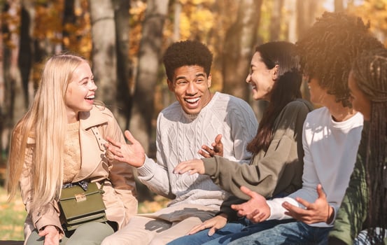 Group of happy international teenagers talking and laughing in park, close up photo