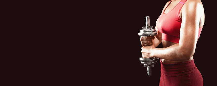 Side view of sporty african girl holding barbell over black background, making work out for shoulders, cropped, panorama with free space photo