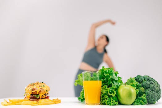 Full-figured woman on a light background talking on the phone with her dietitian, with a burger and healthy food nearby. Perfect for promoting conscious choices towards a healthier diet photo