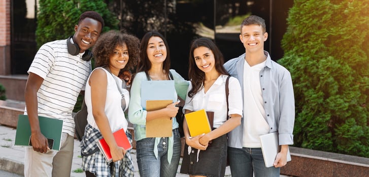 Multiethnic group of students standing outdoors in school campus, looking at camera and smiling photo