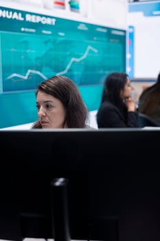 Marketing specialist studying infographics on computer in a monitoring room with big screen, check customer satisfaction from annual data reports. Employee review performance metrics. photo