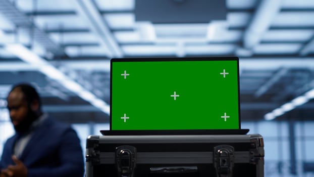 Green screen laptop used by engineers monitoring server room, doing checkup. Focus on chroma key notebook used by IT support employee working in data center facility, camera A close up photo