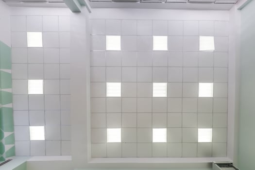 cassette stretched or suspended ceiling with square halogen spots lamps and drywall construction in empty room in house or office. Looking up view photo