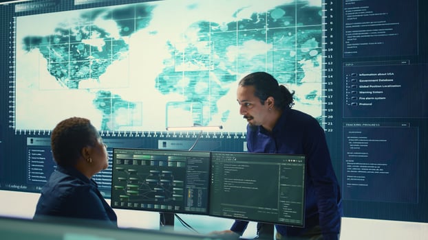 Cyber defense team working in a governmental security operations center. Experts ensuring cybercrime prevention and data breach protection, examining information on a big screen. Camera B. photo